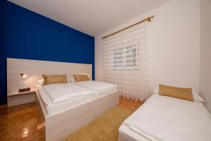 a bedroom with two beds and a blue wall at Apartments Kos in Supetarska Draga