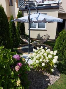 un jardín con banco, sombrilla y flores en Jedrula, en Łeba