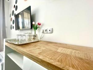 a desk with a television and flowers on it at GlassRoom- Самостоятелна стая Private room in Varna City
