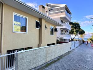 un edificio con una valla al lado de una calle en casa de praia, en Bombinhas