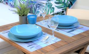 uma mesa de madeira com placas azuis e óculos em La Calita Escondida - Jacuzzi y Cocina en Terraza Privada - Piscina y Parking Gratis em Chiclana de la Frontera