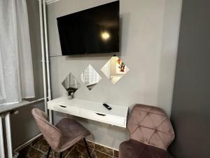escritorio con 2 sillas y TV en la pared en One Room Apartment Decebal, en Bucarest