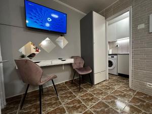 Habitación con escritorio con 2 sillas y TV en la pared. en One Room Apartment Decebal, en Bucarest