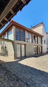 a large stone house with glass doors and windows at Casa do Forno de Cal in Vila do Conde