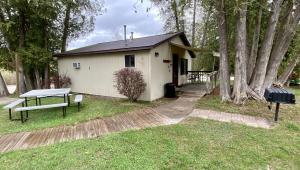 a small white house with a picnic table in front of it at Betsie Riverside Resort in Benzonia