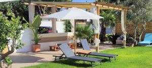 um pátio com 2 cadeiras e um guarda-sol em La Calita Escondida - Jacuzzi y Cocina en Terraza Privada - Piscina y Parking Gratis em Chiclana de la Frontera