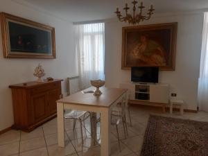 ein Wohnzimmer mit einem Tisch und einem TV in der Unterkunft Maison Santa Giustina in Salò