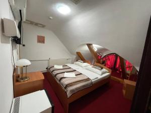 a small room with a bed and a tv at Hotel Minaret&Étterem in Eger