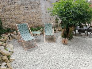 two lawn chairs sitting next to a brick wall at Studio 2 à 4 personnes in Dompierre-sur-Mer