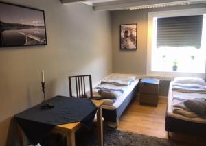a room with two beds and a table and a window at Taras Rom og leiligheter in Kragerø