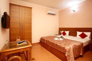 ein Hotelzimmer mit einem Bett und einem TV in der Unterkunft Indira International Inn in Neu-Delhi