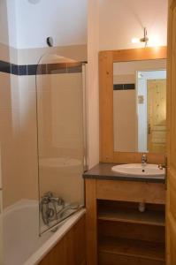 een badkamer met een bad, een wastafel en een spiegel bij T2 6 p - Pieds des pistes - résidence avec piscine in Orcières