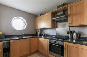 eine Küche mit Holzschränken, einem Waschbecken und einem Fenster in der Unterkunft The Lantern Building in Southampton