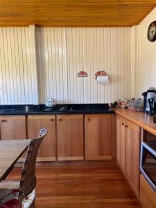 uma cozinha com armários de madeira, uma mesa e um balcão em Mountain House em Bom Jardim da Serra