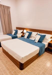 two beds in a room with blue and white at Vaagali Inn in Keyodhoo