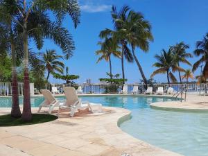 une piscine avec chaises longues et palmiers dans l'établissement appartement au bord de l'eau sxm, à Baie Nettlé