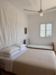 a white bedroom with two beds and a window at Vintage lover's getaway in Antiparos