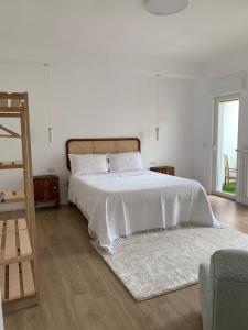 a white bedroom with a bed with a white comforter at Mariluna in Modugno
