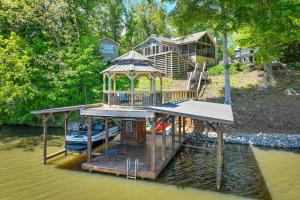 a house on a dock with a boat on the water at Lakefront Vacation Rental with Views and Hot Tub! in Bracey