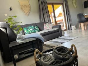 a living room with a couch and a table at Domek z kominkiem nad jeziorem z jacuzzi ogrodowym in Sumowo