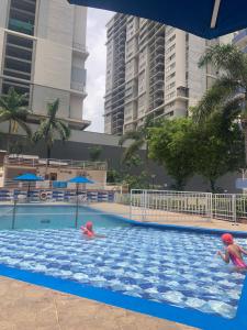 two people swimming in a swimming pool with buildings at Habitaciones vista azul campestre-diagonal a la Foscal in Floridablanca