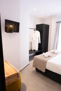 1 dormitorio con 1 cama y TV en la pared en VENUS LUXURY APARTMENT en Ermoupoli