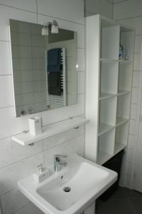 a white bathroom with a sink and a mirror at Apartment Majatalo in Zagreb
