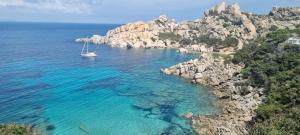 a boat in the water next to a rocky coast at Casa Brì Boutique Rooms in Santa Teresa Gallura