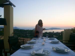 a woman and a child sitting at a table with glasses at serenity villa Aegina fantastic view near the beach in Egina