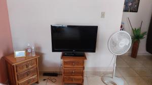 a flat screen tv sitting on a stand with a fan at Tocumen Sweet Home in Cabuya