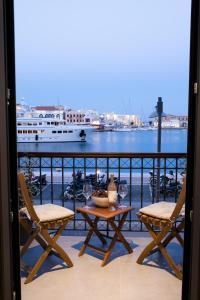 a balcony with two chairs and a table and a boat at VENUS LUXURY APARTMENT in Ermoupoli