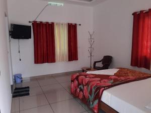 een slaapkamer met een bed met rode gordijnen en een stoel bij MUNNAR FALCUNS in Anachal