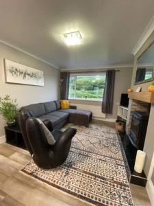 sala de estar con sofá de cuero negro y alfombra en Paddys, en Glenties