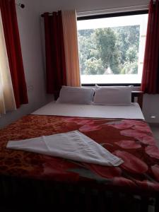 een slaapkamer met een groot bed en een raam bij MUNNAR FALCUNS in Anachal