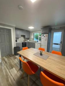 una cocina con mesa de madera y sillas naranjas en Paddys, en Glenties