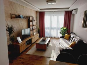 a living room with a couch and a tv at Apartman Kristal in Sremska Mitrovica