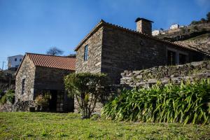 een oud stenen huis met een heuvel op de achtergrond bij Cardenha do Douro in Mesão Frio