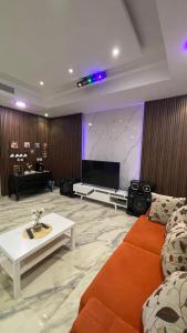 uma sala de estar com um sofá e uma televisão de ecrã plano em درة العروس فيلا الذهبي 38 em Durat Alarous