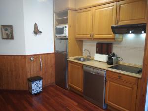 a small kitchen with wooden cabinets and a sink at Apartamento con gran terraza y vistas panorámicas en Taüll, con plaza de parking in Taüll