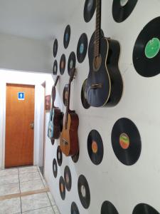 uma parede com guitarras e discos pendurados numa parede em SANTO MAR HOSTEL em Arraial do Cabo