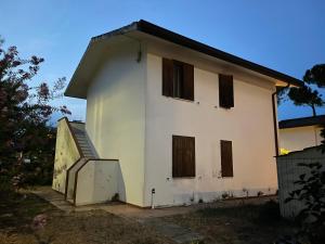 a white house with brown windows and a gate at Villa Kara in Lido degli Scacchi