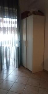 een kamer met een raam met gordijnen en een tegelvloer bij Stanza in appartamento in Latina