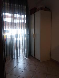 een kamer met een deur en een raam met gordijnen bij Stanza in appartamento in Latina