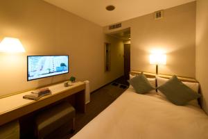 a hotel room with a bed with a desk and a tv at Hotel Resol Machida in Machida