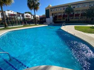 a large blue swimming pool in front of a building at People Homes Bajo Guía in Sanlúcar de Barrameda