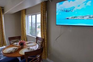 a dining room with a table and a tv on a wall at Nassau Harbour Cozy 2 bedroom Condo in Nassau