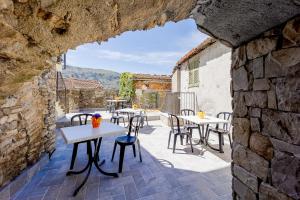 un patio con mesas y sillas y una pared de piedra. en Appartamento Ginny Dachi Farm, en Andora