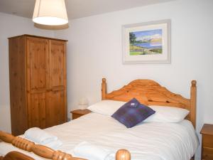a bedroom with a white bed with a wooden headboard at Taigh Na Beadan in Valtos