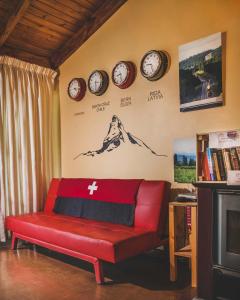 sala de estar con sofá rojo y relojes en la pared en Casa Suiza, en Santa Cruz