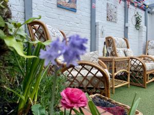 a patio with wicker chairs and purple flowers at Seaside Homestay - Ensuite twin room with Kitchenette in Paignton